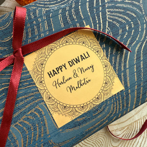 Gift box with a 'Happy Diwali' tag and red ribbon on a blue patterned background