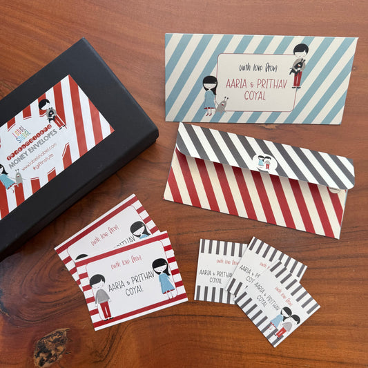 Set of personalized envelopes and cards with striped designs on a wooden surface