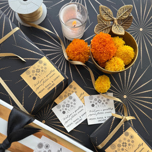 Decorative gift wrapping with flowers, ribbons, and candles on a patterned surface