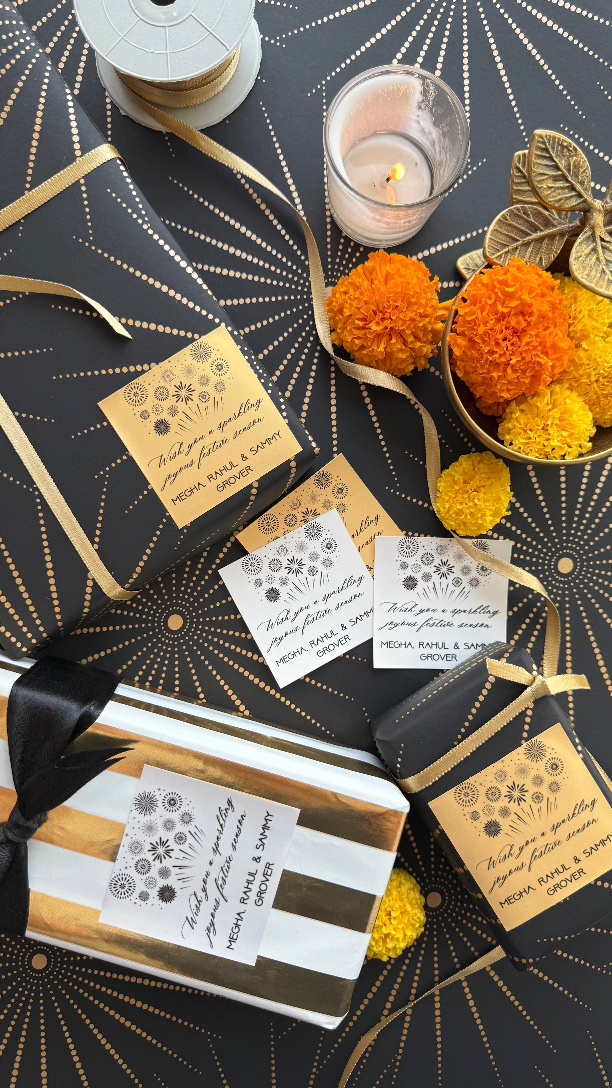 Decorative gift packaging with gold ribbons, candles, and floral elements on a black and gold patterned background.