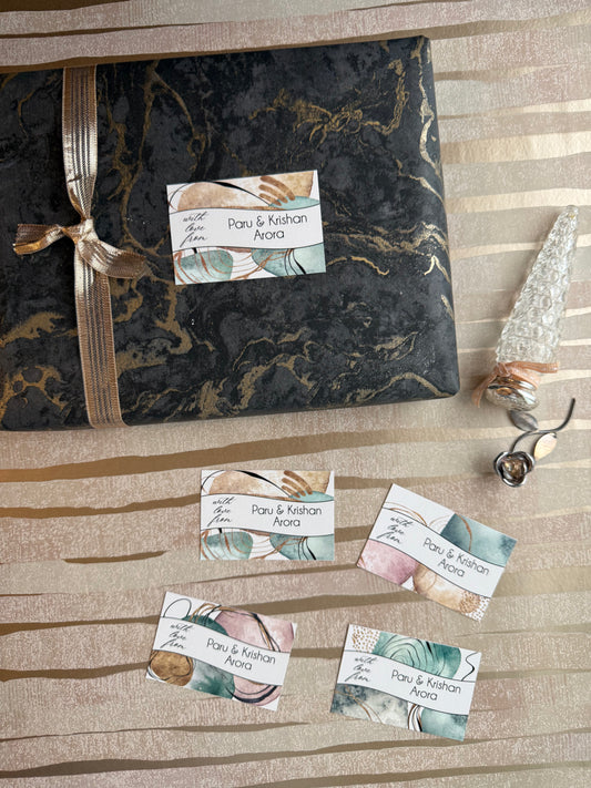 A wrapped gift box and several small personalised gift tags arranged on a beige striped fabric background. 