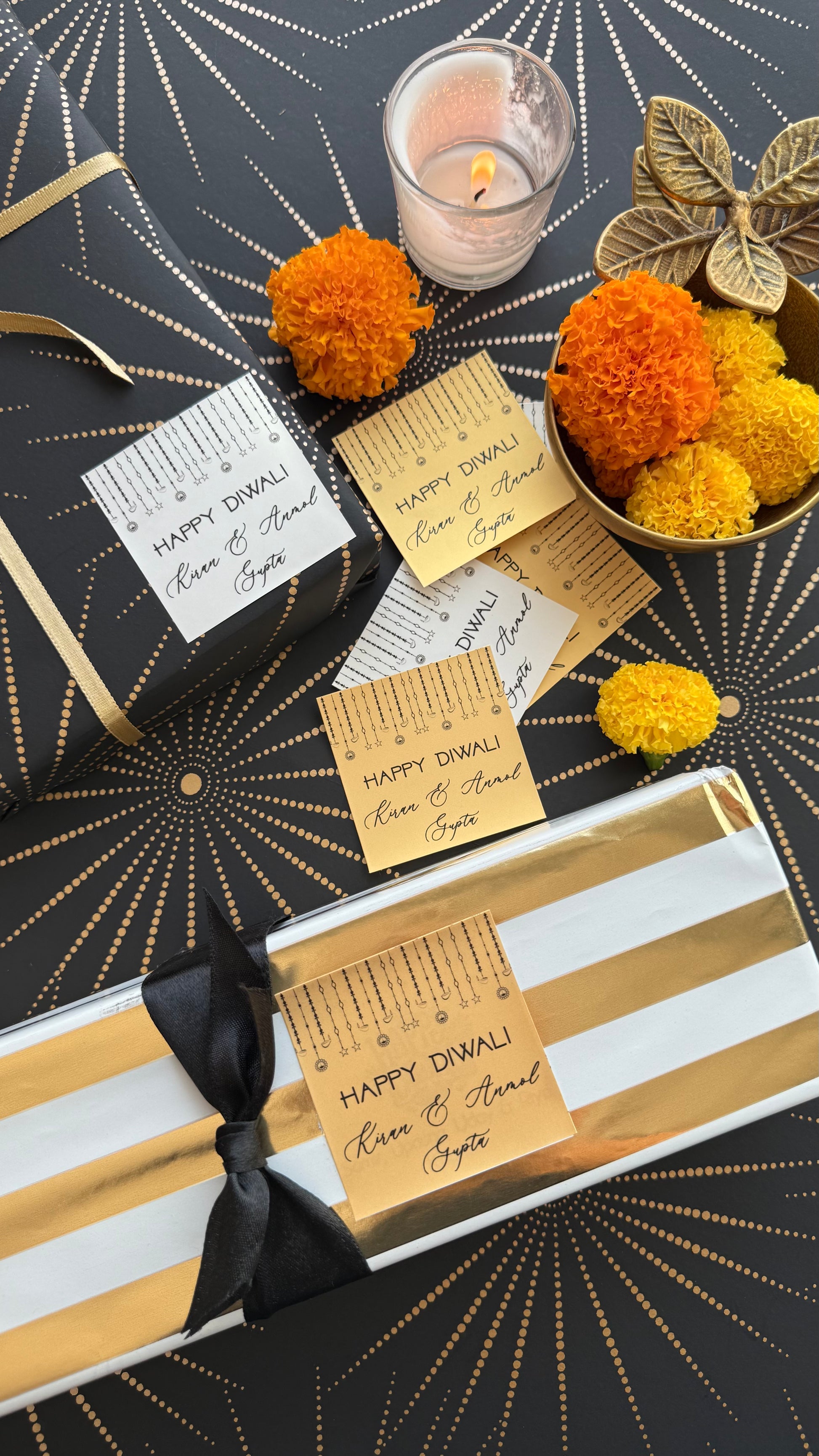 Decorative gift wrapping with gold ribbon, black bow, and marigold flowers on a black and gold patterned background.