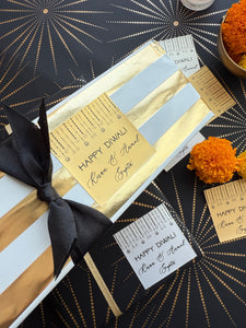 Gift box with gold card and black ribbon on a decorative background