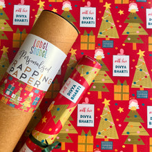A roll of personalized wrapping paper with Christmas trees and the text 'With love from Diva Bharati' on a red background, indicating it is wrapped around a gift.