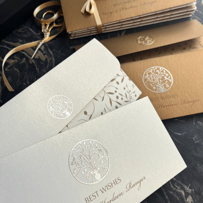 A stack of envelopes with a Tree of Life design, featuring gold accents on the front and back, placed on a marble surface.