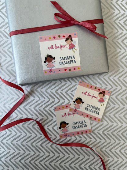A silver gift box tied with a red ribbon and two matching personalized gift tags with cartoon girl illustrations and the text 'with love from SAMAIRA DASCUPIA' on a gray patterned surface.
