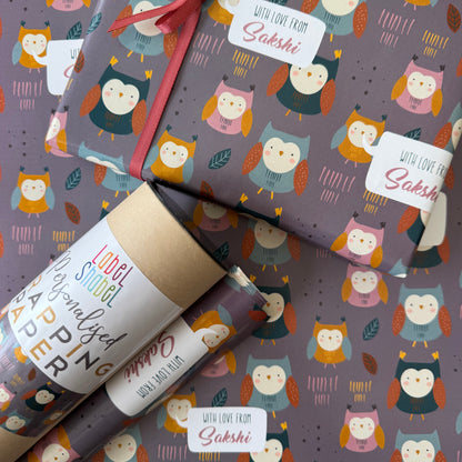 Owl-themed wrapping paper shown wrapped around gift boxes, with a roll of matching paper in the foreground and printed labels reading 'WITH LOVE FROM Sakshi'.