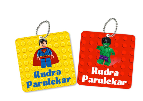 Two square metal bag tags with Lego Avengers character designs. One tag features a superhero character in red and the other features a character in green, both with the text 'Rudra Parulkar'.