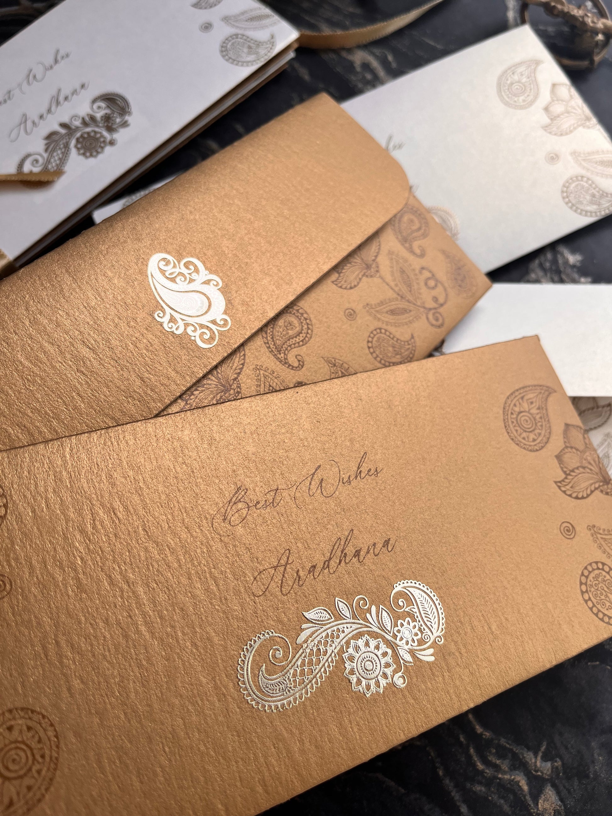 Invitations with paisley designs on a dark background