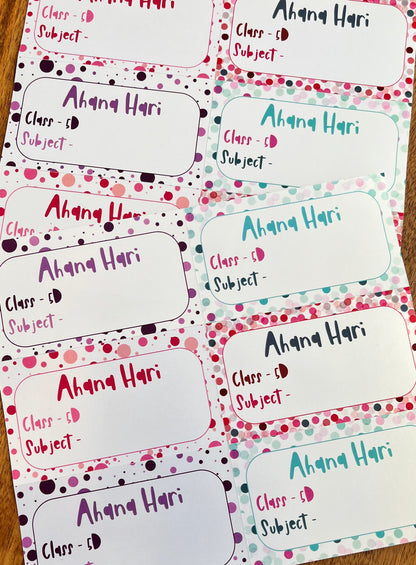 A set of printed class roster labels or name tags laid out on a wooden surface. Each label has a white rounded rectangle body with a decorative border of pink, purple, and teal polka dots on a white background.