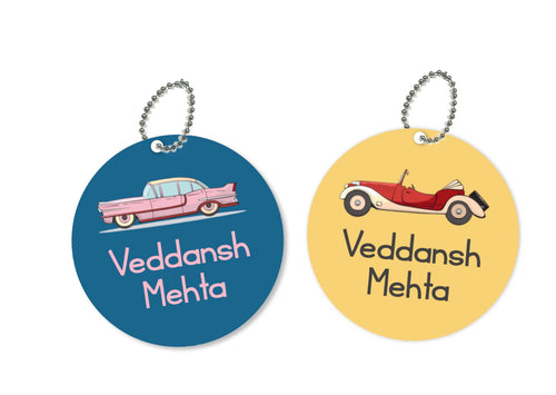 Two round metal bag tags with a vintage car and a vintage motorcycle design, one tag with the text 'VEDANSH METHA' and the other with 'METHA VEDANSH'. Both have a yellow background with a blue and red design.