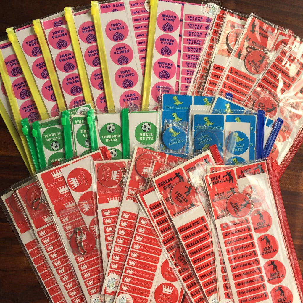 Assorted colorful name labels in various shapes and designs, primarily in pink, yellow, red, green, blue, and white, displayed on a table.