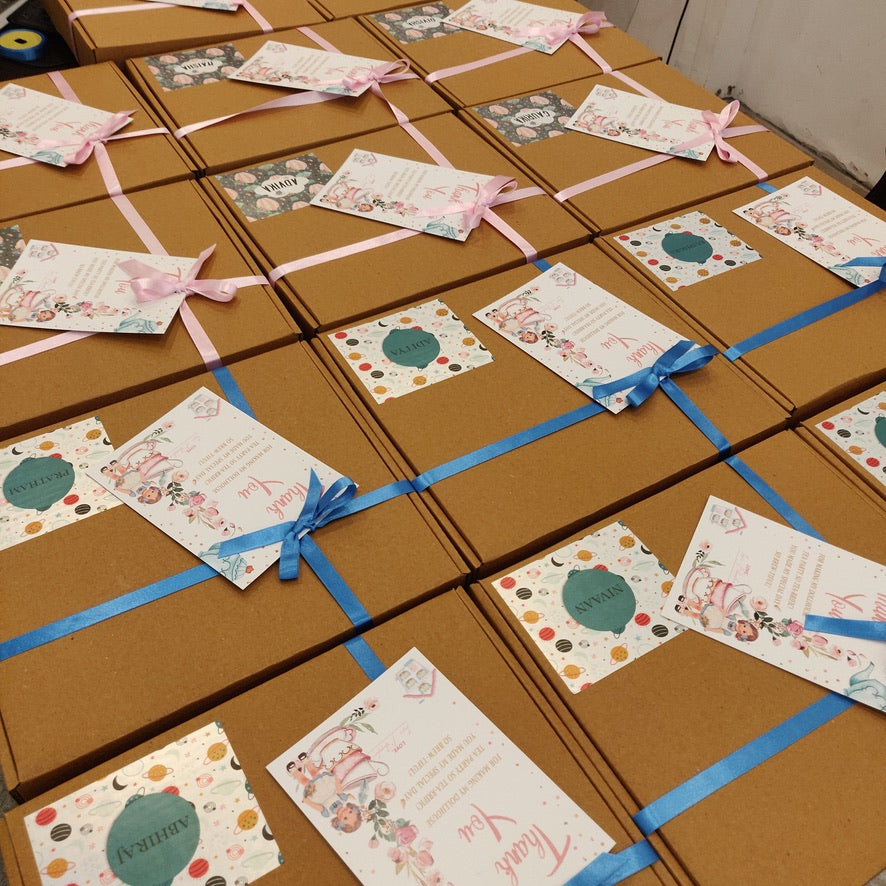 A collection of brown gift boxes tied with blue ribbons, each featuring a personalized label design.