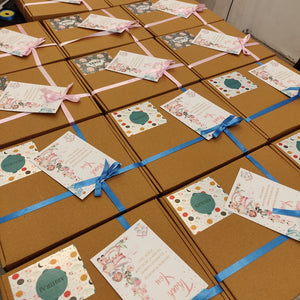 A collection of brown gift boxes tied with blue ribbons, each featuring a personalized label design.