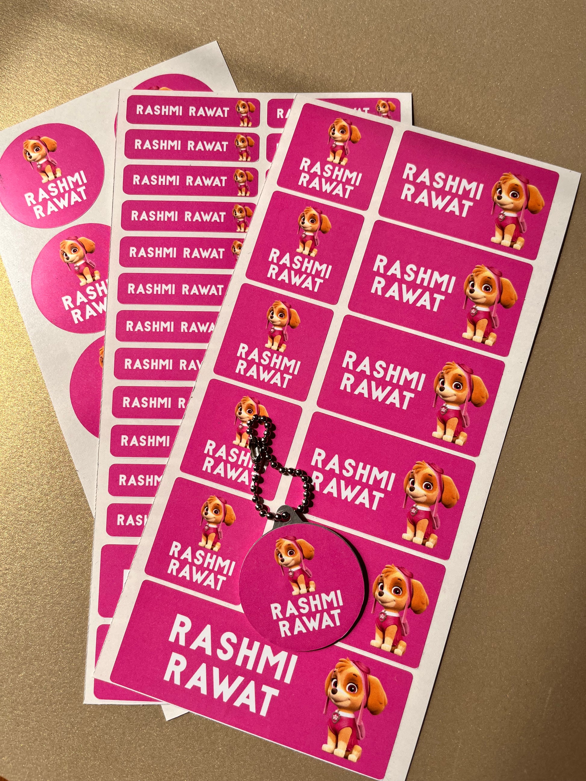 Sheet of pink stickers with a cartoon character and a name on a beige background