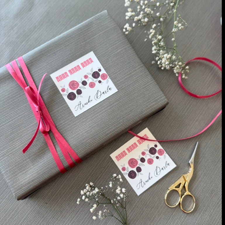 A wrapped gift box in gray paper with a bright pink ribbon and two decorative gift tags 