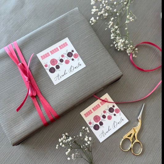 A wrapped gift box in gray paper with a bright pink ribbon and two decorative gift tags 