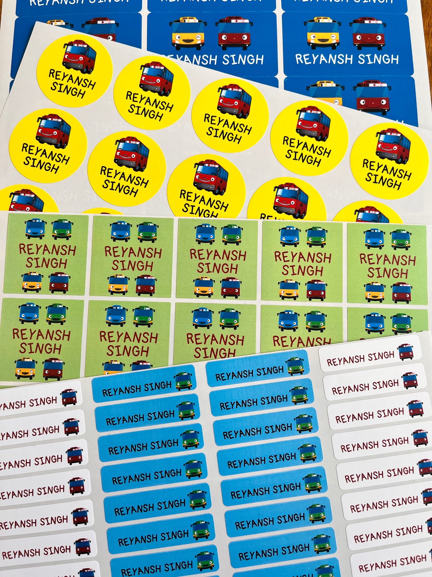 waterproof name labels with bright blue green yellow colours featuring tayo bus cartoons, personalised with a child's name