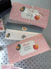 Two pink gift envelopes with polka dots and a name on a gray surface.