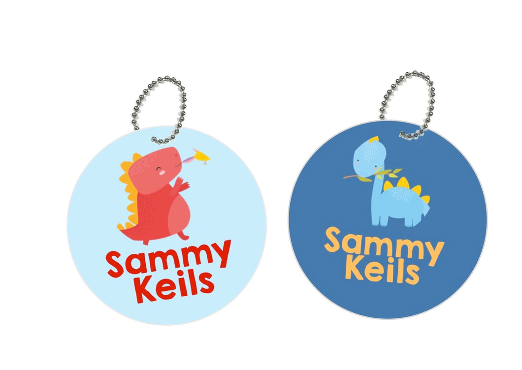 pair or round metal bag tags for kids in light and dark blue with cute dinosaurs